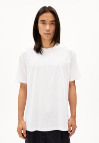 Witte katoen t-shirt met korte mouwen, ronde hals, relaxte pasvorm, zachte textuur en subtiele stikseldetails nabij de zoom.