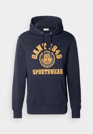 Navy blue hoodie made of cotton, featuring a front pocket, drawstring hood, and vintage-style yellow print with logo and year 1949.