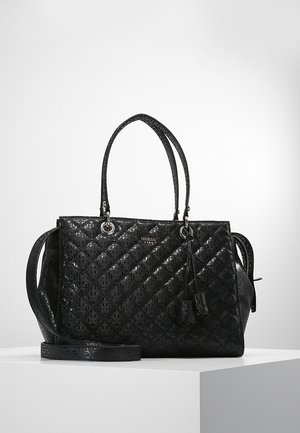 Czarna torebka GUESS z tłoczonym wzorem logo, podwójnymi górnymi uchwytami oraz odpinanym paskiem na ramię na białym piedestale.