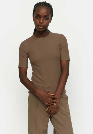 Brown ribbed t-shirt with short sleeves, round neckline, and a fitted shape. Worn with matching taupe trousers for a cohesive look.