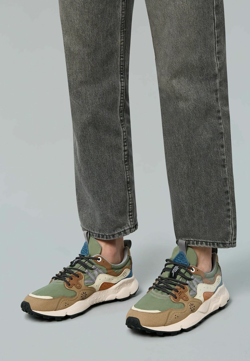 Sneaker multicolori con superiore in rete, scamosciato e sintetico in verde, marrone e blu, dotati di lacci neri e suola in gomma testurizzata.