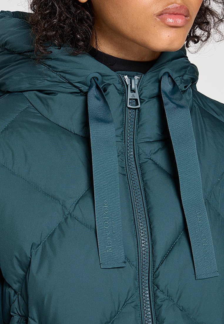 Turkusowa kurtka puchowa o pikowanym wzorze, z zamkiem z przodu i podwójnymi sznurkami z materiału przy szyi. Wyraźnie miękka struktura i ciepła izolacja.