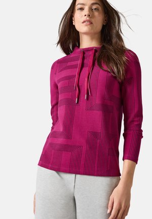 Hoodie fuchsia à manches longues avec un motif géométrique de lignes noires, cordon de serrage ajustable et tissu doux. Associé à un bas gris clair.