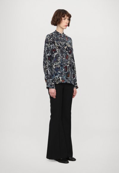 Floral-patterned, long-sleeve blouse in navy, featuring a button-up collar and relaxed fit, worn with black, flared trousers and black flats.