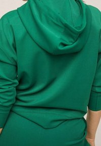 Groene hoodie van gestructureerde stof, met een grote capuchon en een losse pasvorm. Het ontwerp heeft verlaagde schouders en een subtiele naaddetail.