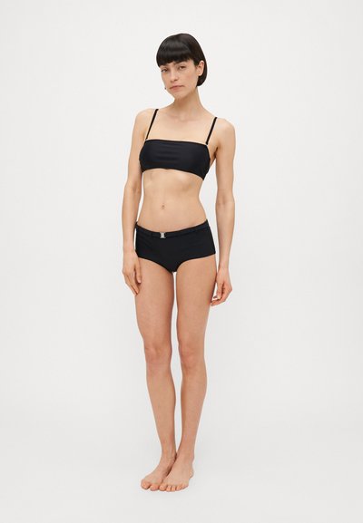 Melna bikini komplekts ar bezplecu augšu un augstām biksītēm. Gluda auduma, minimālisma dizains un neliela metāla akcenta detaļa jostā.