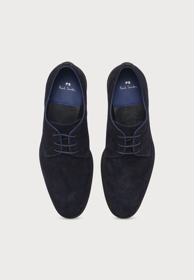 Paire de chaussures habillées en daim noir à lacets avec doublure intérieure bleue et marquage « PS Paul Smith » à l’intérieur, vues de dessus sur fond blanc.