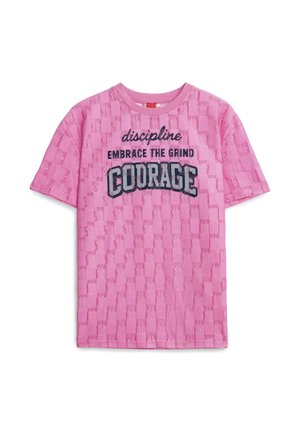 Růžová košile s krátkými rukávy s texturovaným kostkovaným vzorem a černým nápisem "discipline EMBRACE THE GRIND COURAGE" přes přední část.