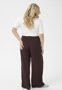 Maroon wide-leg pants with a relaxed fit and an elastic waistband. The top is white, short-sleeved, with a smooth texture.