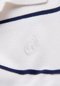 Polo bianco con striscia orizzontale navy, dotato di logo ricamato. La trama è fine a maglia, con una finitura liscia.