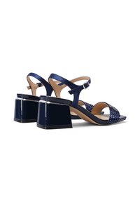 Sandali blu navy con finitura lucida, caratterizzati da un tacco quadrato spesso, design con fasce intrecciate e una fibbia regolabile alla caviglia.