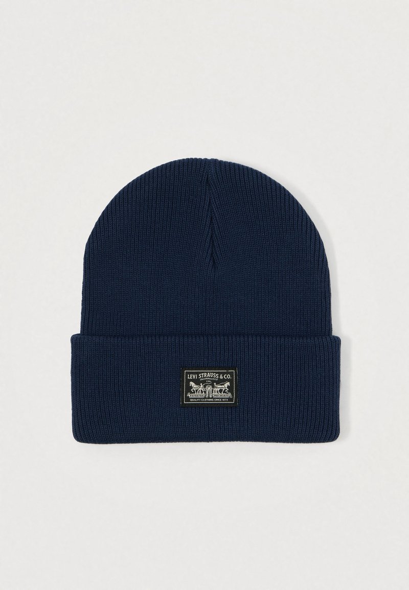 Dark blue knit beanie with a folded cuff. Features a rectangular black label with white text and a graphic of horses.