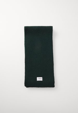 Écharpe en tricot côtelé vert foncé pliée avec une petite étiquette rectangulaire blanche portant la mention "ARKK" sur fond blanc.