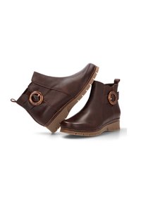 Botas de cuero marrón hasta el tobillo con punta redondeada, tacón de cuña, panel lateral y detalle circular en el tobillo. Suela de goma texturizada.
