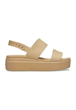 Sandalia de plataforma beige con dos tiras anchas, correa trasera ajustable y suela gruesa, con el logo sutil de "crocs" en el lateral.