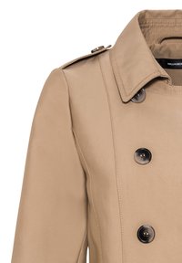 Imperméable beige avec des boutons noirs à double boutonnage, large col, épaulettes et couture visible sur un tissu lisse.