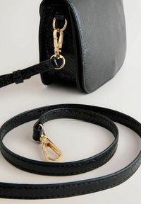 Černá kožená kabelka s pevnou strukturou, se zlatým kovovým zapínáním a odnímatelným páskem s texturovaným povrchem.