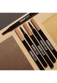 Six stylos à sourcils avec des pointes fines dans des teintes allant du brun clair au brun moyen. Des tubes noirs arborant une marque audacieuse, placés sur des fonds colorés texturés.