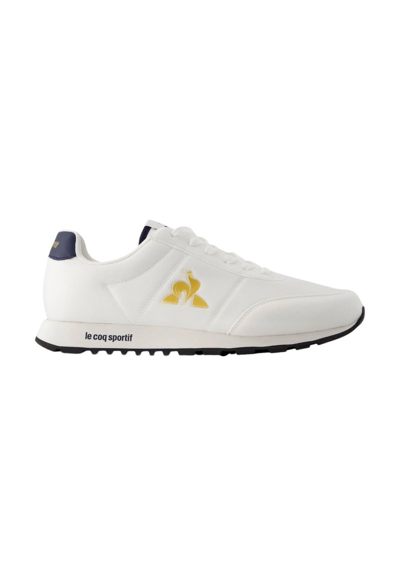 Sneaker atletico bianco con logo giallo e blu scuro, design con lacci, materiale in pelle liscia e suola in gomma nera con battistrada testurizzato.