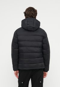 Μαύρο μπουφάν με κουκούλα, με ραμμένο σχέδιο, ριμπ μανσέτες και απαλό, ελαφρύ ύφασμα. Η πίσω όψη δείχνει κομμένη γραμμή.