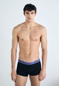 Schwarze Boxer-Briefs mit einem grauen Bund, auf dem "HUGO" in Rot steht. Der Stoff ist glatt, hat ein figurbetontes Design und keine sichtbaren Muster.