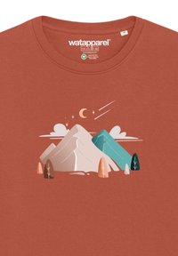 T-shirt couleur rouille avec un graphisme de montagne en teintes pastel, accompagné d'arbres stylisés et d'un croissant de lune en accent au-dessus.