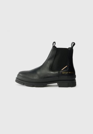 Black leather Chelsea boots with side elastic panels, thick rubber sole, pull tabs, and metallic branding on the heel.