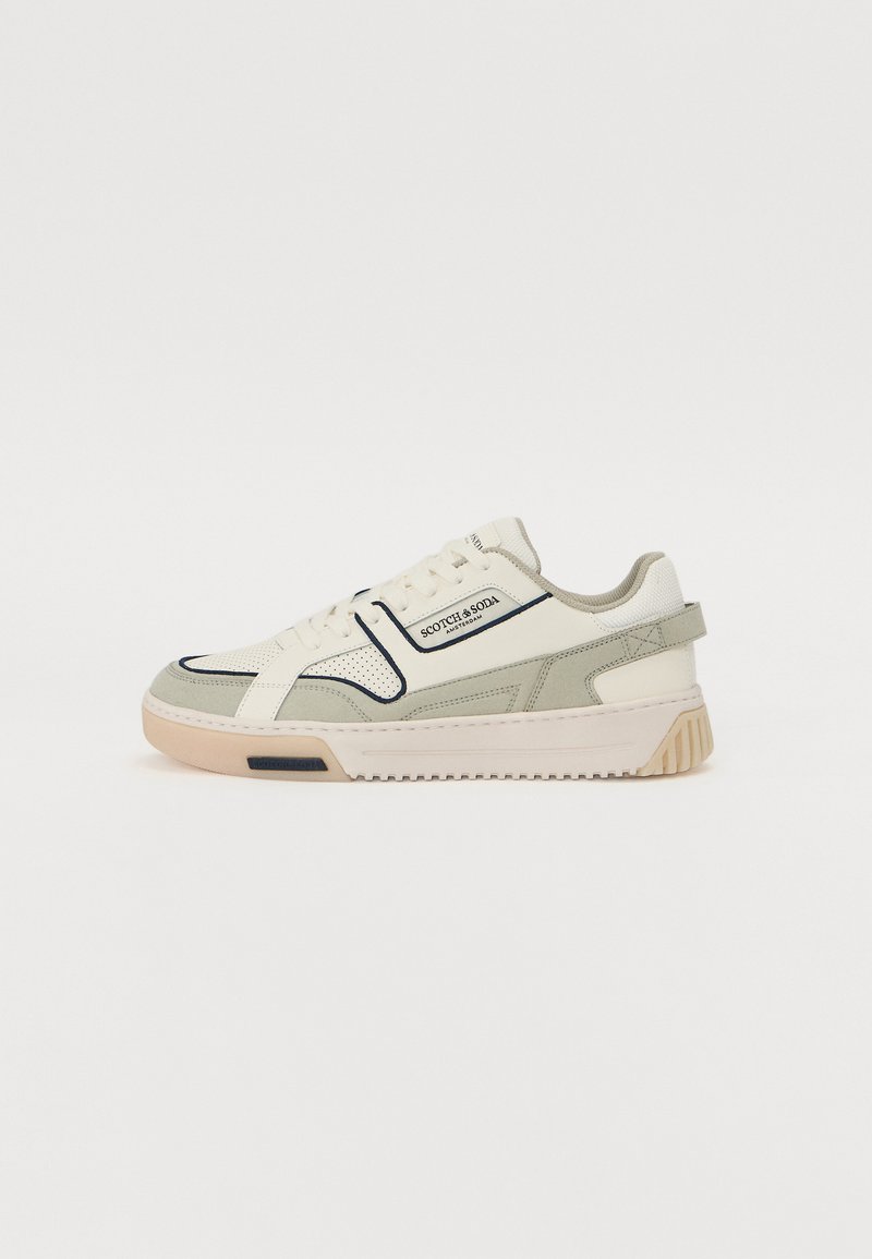 Hvide sneakers med grå ruskindselementer, mesh-struktur og sorte detaljer. Har en tekstureret gummisål og et logo på siden.