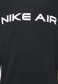 Svart tyg med "NIKE AIR" tryckt i stora vita versaler över bröstområdet.