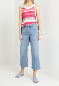 Rood en grijs gestreepte tanktop met witte rand, hoog-gewogen lichtblauwe wijde jeans en lichtblauwe instapsandalen. Eenvoudige, casual outfit.