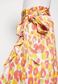 Gonna a fiori in tessuto leggero, con un vivace motivo rosa, giallo e verde, dotata di un fiocco annodato e dettagli a ruches sul bordo.