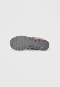 Shoe sole featuring a rugged gray rubber design with deep treads and a textured surface; light brown upper material visible along the edges.