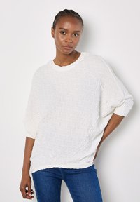 Weißer strukturierter Pullover mit Rundhalsausschnitt und überschnittenen Schultern, mit lockerer Passform und gerippten Akzenten an den Bündchen und dem Saum.