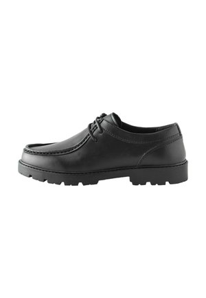 Zwarte leren veterschoen met dikke rubberen profielzool, ronde neus en contrasterende stiksels op witte achtergrond.
