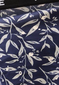 Tela azul marino con estampado botánico blanco que presenta hojas y bayas en un patrón repetitivo.