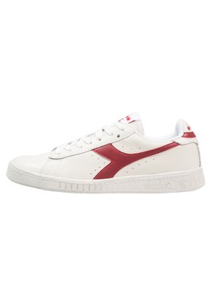 Sneaker in pelle bianca con una striscia diagonale rossa, superficie testurizzata, punta tonda, suola piatta bianca e dettagli perforati sulla parte superiore.