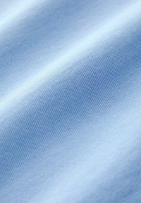 Gros plan sur un tissu bleu clair lisse avec une texture fine en maille et des plis doux.