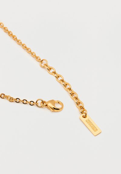 Κολιέ αλυσίδας σε χρυσούς τόνους με κούμπωμα τύπου αστακό και ορθογώνια ετικέτα με χαραγμένο το "MOSCHINO" σε λευκό φόντο.