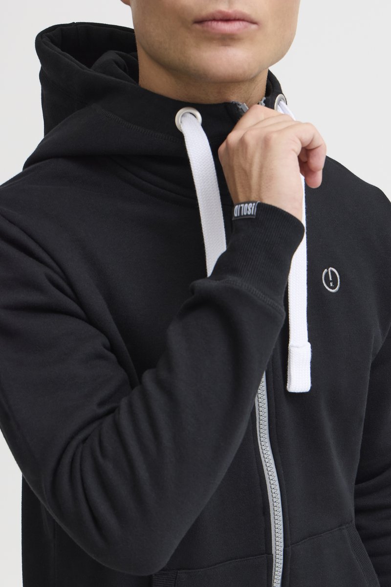 Sudadera negra con cremallera y cordones blancos, puños acanalados y un logo en el pecho. Fabricada en un tejido suave y texturizado.