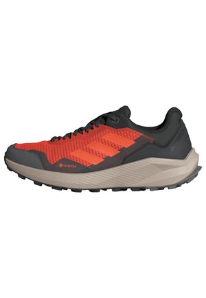 Heren trailrunning schoen met een rode mesh bovenkant en zwarte accenten, GORE-TEX merknaam, en een beige rubberen zool met een gestructureerde grip.