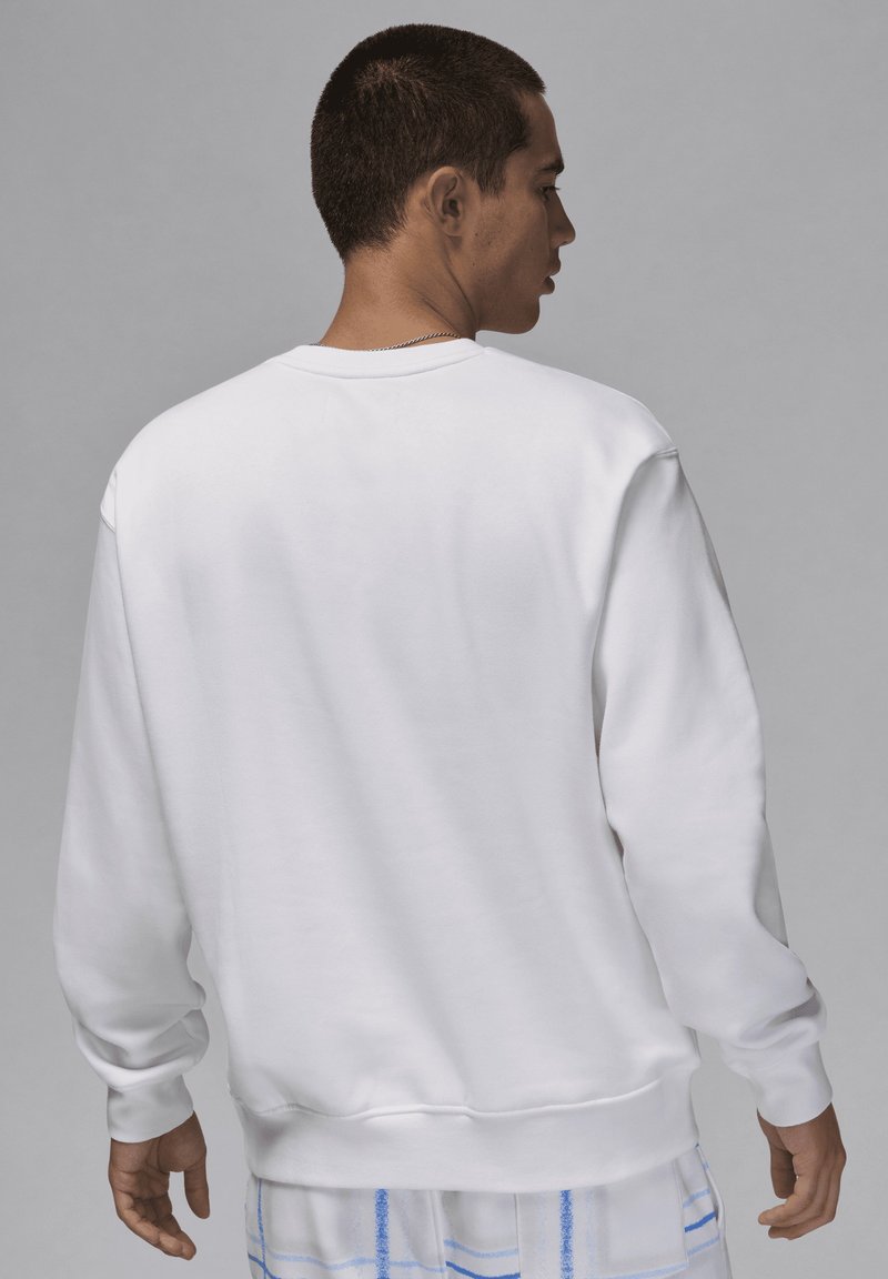 Sweatshirt blanc avec col rond, manches longues et poignets côtelés. Texture lisse avec une coupe décontractée, conçu pour un usage quotidien.
