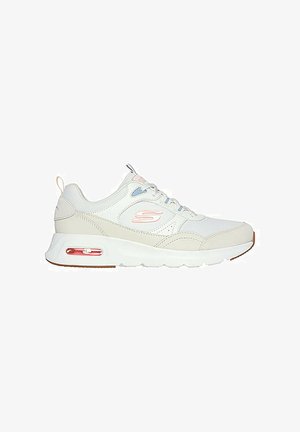 Zapatilla blanca con acentos gris claro, cuenta con una suela acolchada, diseño de cordones y una unidad de aire visible en el talón con detalles en rosa.