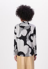 Camicia a maniche lunghe con un motivo astratto in bianco e nero, realizzata in tessuto leggero, con colletto a punta e polsini abbottonati.