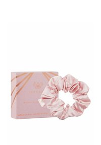 Różowa satynowa gumka do włosów o gładkiej fakturze, prezentowana obok jasnoróżowego pudełka z geometrycznymi złotymi akcentami i brandingiem.