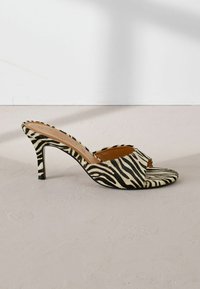 Mule à talons hauts ouvert en imprimé zèbre noir et ivoire, en matériau texturé doux et avec un talon stiletto fin.