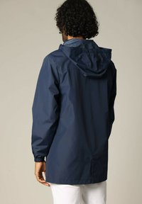 Veste imperméable marine avec capuche, en matériau léger, poignets élastiques et coupe ample. Texture lisse avec des coutures et des détails de conception minimaux.