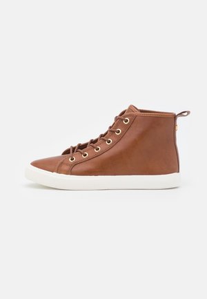 Brązowy, skórzany sneaker typu high-top z białą gumową podeszwą, złotymi oczkami na sznurówki, brązowymi sznurowadłami i zawieszką z tyłu na pięcie na białym tle.
