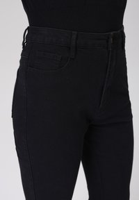 Sorte høye midjejeans laget av denim, med en jevn tekstur, klassisk fem-lomme-design og en subtil sømdetalj.