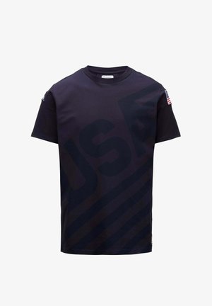 T-shirt noir manches courtes col rond avec grand texte foncé "USA" et rayures diagonales, patch du drapeau américain sur la manche droite.