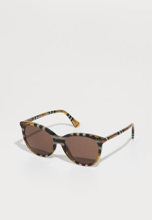 Gafas de sol de estilo cat-eye con un marco a rayas multicolores en negro, marrón y ámbar; lentes tintados en marrón; y varillas con diseño.